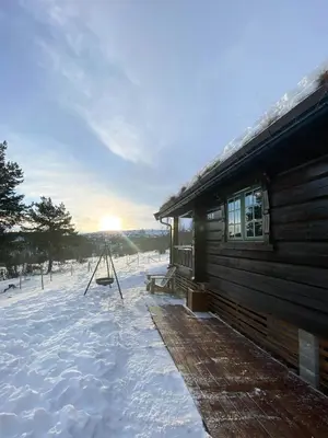 a cabin in the snow with the sun in the background at Charming Log Cabin In Jøldalen in Rennebu