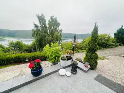 a garden with potted plants and a view of a river at Apartment by the fjord, with boat and jacuzzi included in Larsnes
