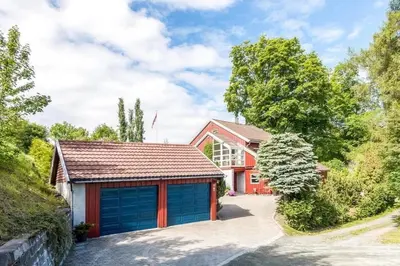 a red house with two garage doors in a driveway at 5 room apartment for Ski-World Championship in Trondheim