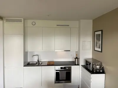 a kitchen with white cabinets and a sink and a microwave at Apartment in Trondheim, Tiller in Trondheim