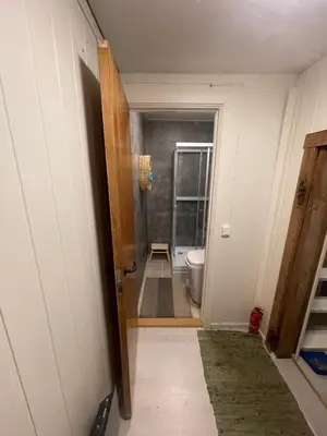 a hallway with a bathroom with a toilet and a door at Bekkvang Fjøs Tiny House in Trysil