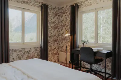a bedroom with a bed and a desk and windows at Villa Fjellheim in Luster