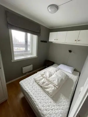 a bedroom with a bed with white sheets and a window at Geilo Gaarden - Geilo sentrum in Geilo