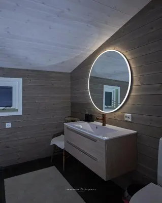 a bathroom with a sink and a round mirror at Rjånes Ferie og Konferansesenter in Ørsta