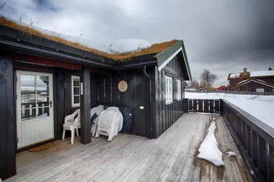 a black house with a white dog on a deck at Family-Friendly Cabin With Stunning Outdoor Access in Beitostøl