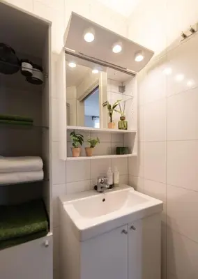 a white bathroom with a sink and a mirror at Unique apartment in midtown in Trondheim