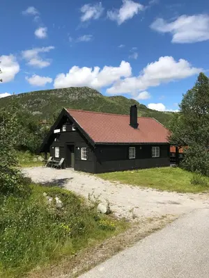 a black house with a hill in the background at Cozy Cabin Hovden Fjellpark 71 in Hovden