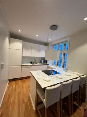 a kitchen with white cabinets and a table with chairs at Apartment near City Center in Trondheim