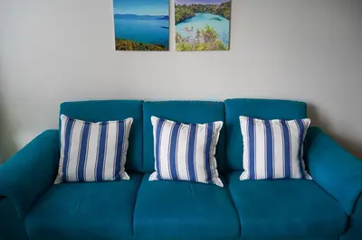 a blue couch with three pillows on it at Solrik leilighet på Byåsen in Trondheim