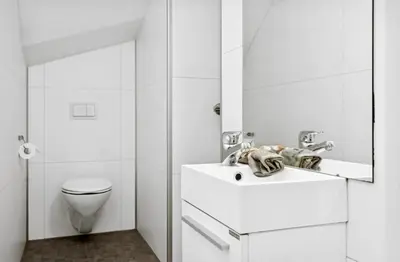 a white bathroom with a toilet and a sink at Modern apartment close to the city center in Trondheim