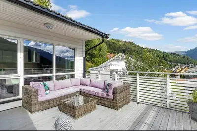 a patio with a couch and a table on a deck at 4 roms leilighet ved Fosshaugane Campus in Sogndal