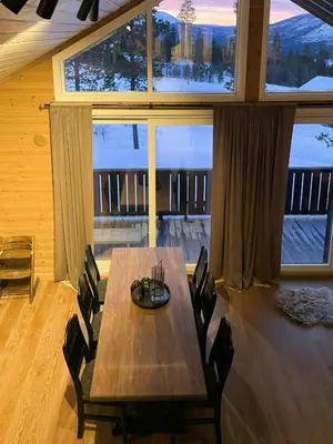 a wooden table and chairs in a room with a large window at Modern Cabin At The Gateway To Jotunheimen in Randsverk
