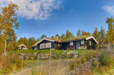 a house on a hill with a fence in front of it at Charming Cabin Near Jotunheimen Trails in Beitostøl