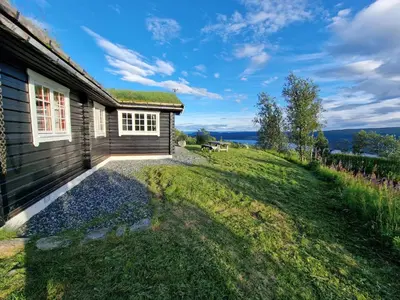 a house with a grassy yard next to a building at Charming Cabin Near Jotunheimen Trails in Beitostøl
