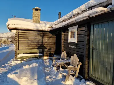 a log cabin in the snow with a bench at Charming Cabin Near Jotunheimen Trails in Beitostøl