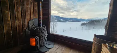 a fireplace in a cabin with a view of a snow covered window at The blue room at Vevstogo - cosy with a mesmerizing view, sauna and eco living in an old school house in Løken