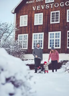 two women and a child standing in the snow in front of a building at The blue room at Vevstogo - cosy with a mesmerizing view, sauna and eco living in an old school house in Løken