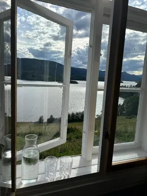 a window with glasses and a view of the water at The blue room at Vevstogo - cosy with a mesmerizing view, sauna and eco living in an old school house in Løken