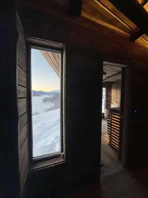 a window in a cabin with a view of the snow at The blue room at Vevstogo - cosy with a mesmerizing view, sauna and eco living in an old school house in Løken