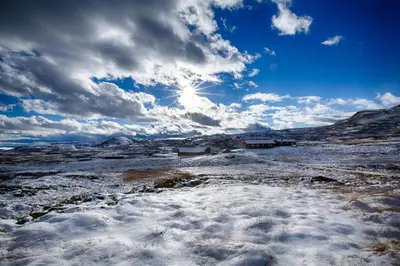 a snow covered field with the sun in the sky at Modern Cabin At The Foot Of Bitihorn in Beitostøl