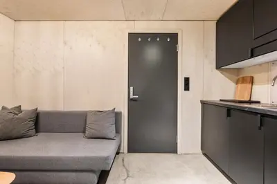 a living room with a gray couch and a door at Comfy studio apartment 200m from bryggen in Bergen