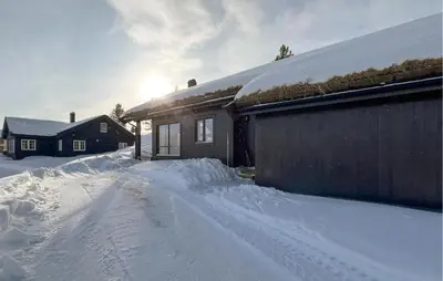 a house is covered in snow next to a building at Gorgeous Home In Kvam With Sauna in Kvam