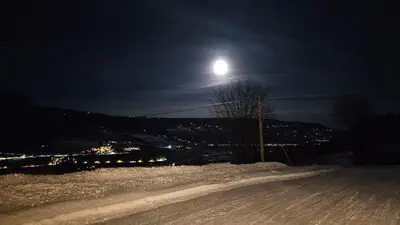 a full moon over a snowy road at night at Leilighet i Sør-Fron kommune in Sør-Fron