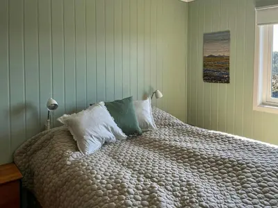 a bedroom with a bed with white sheets and a window at Seaside Cabin With Archipelago Views In Radøy in Bøvågen