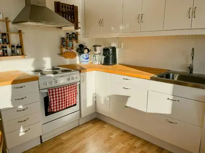 a kitchen with white cabinets and a stove and a sink at Seaside Cabin With Archipelago Views In Radøy in Bøvågen