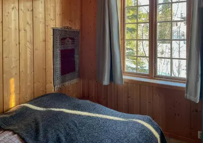 a bedroom with wooden walls and a bed with a blanket at Modernized Cabin At Norefjell With View in Eggedal