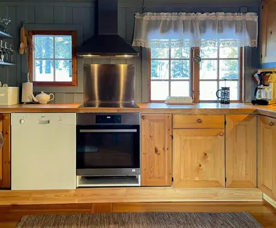 a kitchen with wooden cabinets and a stove top oven at Modernized Cabin At Norefjell With View in Eggedal