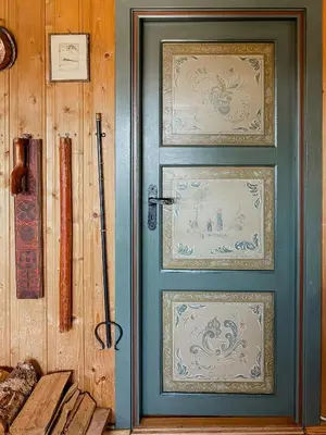 a green door with paintings on it next to a wall at Modernized Cabin At Norefjell With View in Eggedal