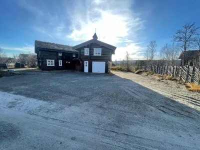 a house on a dirt road next to a fence at Charming Timber Lodge For Gathering And Celebrations in Beitostøl
