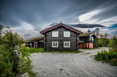a wooden house sitting on top of a gravel road at Charming Timber Lodge For Gathering And Celebrations in Beitostøl