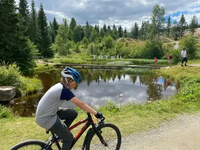 a young boy riding a bike next to a pond at Modern Apartment With Views Of Trysil Mountain in Trysil