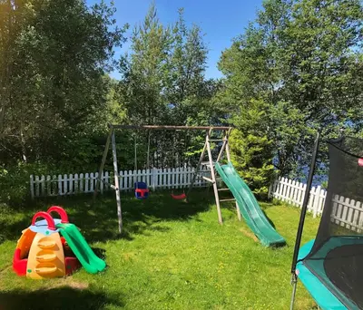 a playground with two swings in a yard at Child-friendly holiday home in Ålesund