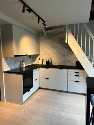 a kitchen with white cabinets and a staircase at Central apartment in idyllic Bakklandet in Trondheim