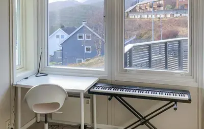 a desk in front of two windows with a keyboard at Lovely Home In Flaktveit With Wifi in Blinde