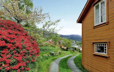 a dirt road next to a house with red flowers at 3 Bedroom Lovely Home In Valen in Valen