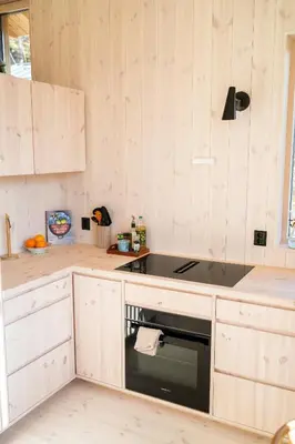 a kitchen with wooden cabinets and a stove top oven at The Crux Nordic Design Mountain Cabin in Åndalsnes