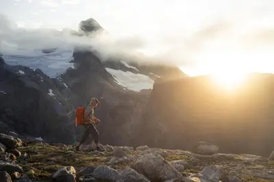 a man walking on top of a mountain at sunset at The Crux Nordic Design Mountain Cabin in Åndalsnes