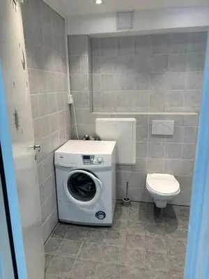 a bathroom with a washing machine and a toilet at studio apartment 24 sqm in Trondheim