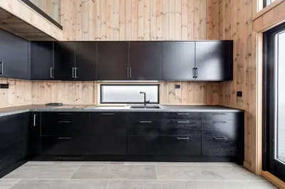 a kitchen with black cabinets and a window at The Holiday - Panorama Lodge in Lampeland