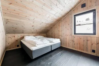 a bed in a wooden room with a window at The Holiday - Panorama Lodge in Lampeland