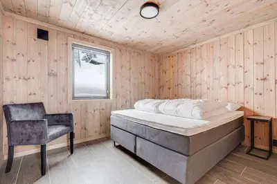 a bedroom with a bed and a chair in it at The Holiday - Panorama Lodge in Lampeland