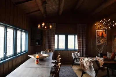 a dining room with a wooden table and windows at Sjarmerende hytte på Geilo med 5 soverom in Geilo