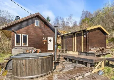 a cabin with a hot tub and a wooden deck at Peaceful Cabin With Spa On Osterøy in Bruvik