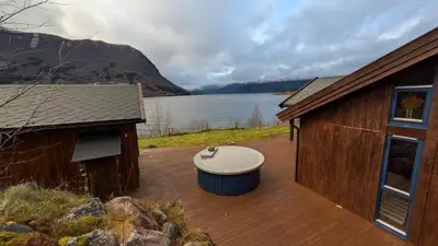 a wooden deck with a bath tub next to a building at Flott hytte i Vistdal, Romsdal in Myklebostad