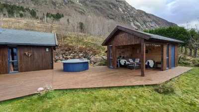 a wooden deck with a hot tub and a house at Flott hytte i Vistdal, Romsdal in Myklebostad