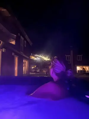 a woman sitting in a pool at night at Harmony in Geilo, modern and cozy cabin with jacuzzi in Geilo